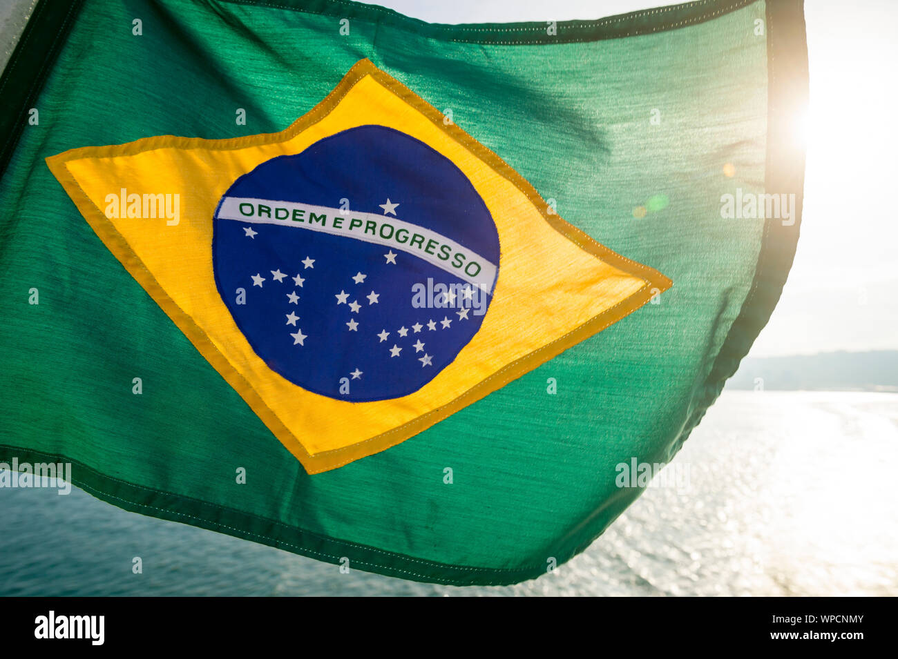 Golden Hintergrundbeleuchtung Blick auf dicke texturierte Flagge von Brasilien fliegen im Freien in tropischen brasilianischen Sonnenlicht Stockfoto