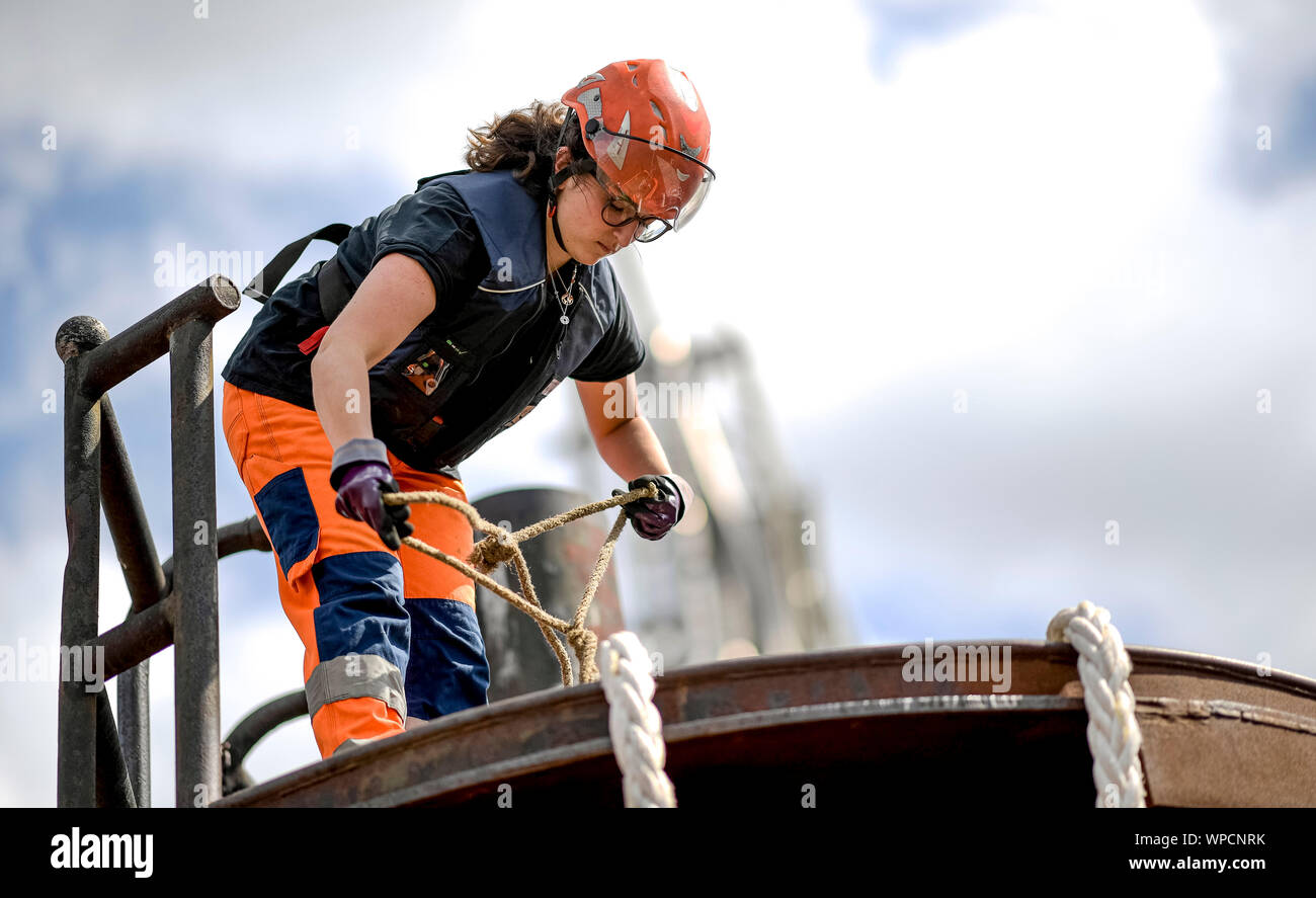 Hamburg, Deutschland. 12 Aug, 2019. Fanny Löwenstrom, festmacher Seil im Hamburger Hafen, zieht ein Seil auf einem Delphin (ein Haufen in den Hafen Boden zur Befestigung von Schiffen Gerammt). Die Verankerung Job ist eine der härtesten und die meisten traditionellen im Hafen. Für eine lange Zeit eine reine Männerdomäne, Frauen sind auch Teil von ihr. Quelle: Axel Heimken/dpa/Alamy leben Nachrichten Stockfoto