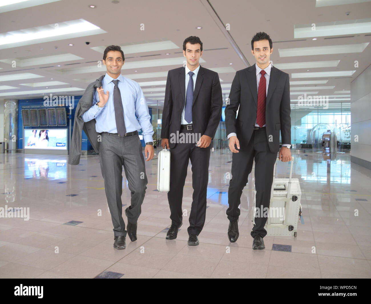 Drei Geschäftsleute, die in einem Flughafen zu Fuß unterwegs sind Stockfoto