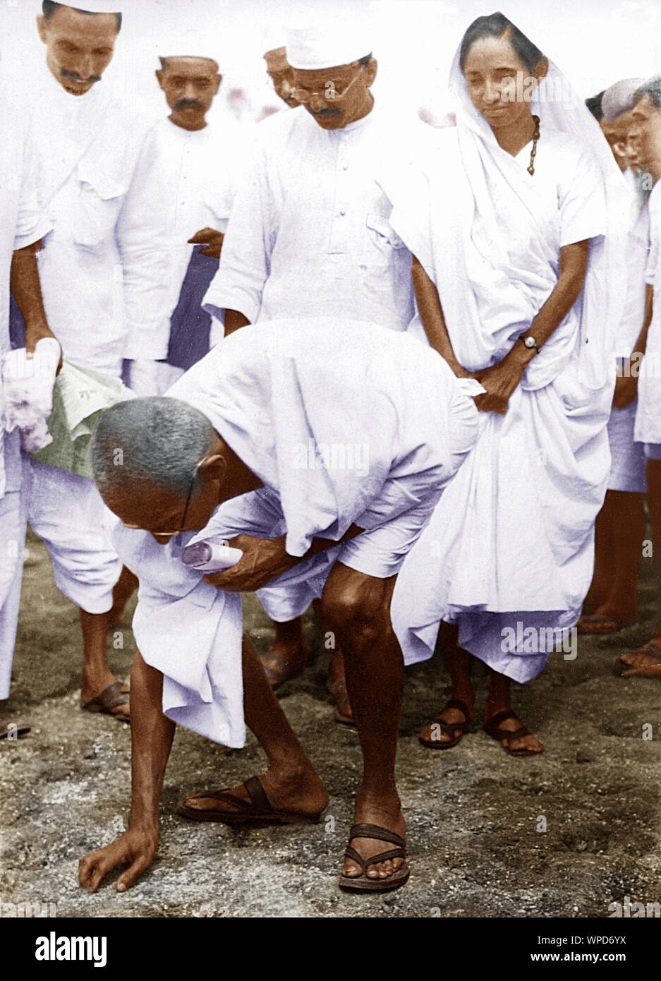 Mahatma Gandhi bricht das Salzgesetz, indem er einen Klumpen natürlichen Salzes aufnimmt, Dandi, Indien, 6. April 1930, Altes Vintage 1900s Bild Stockfoto