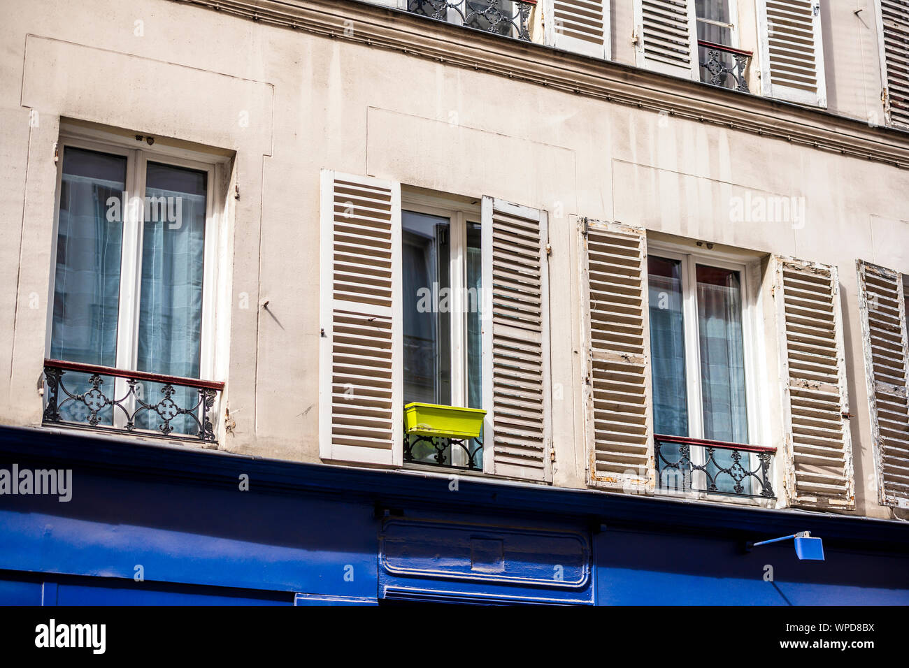 Blumen Topf für Blumen und Pflanzen stehen vor einem Fenster mit Fensterläden aus Holz, die sich auf feste Metall Felgen von einem improvisierten Balkon an der Fassade eines pl ausgesetzt Stockfoto