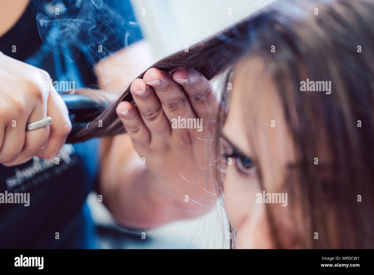 Friseur mit Bügeleisen auf das Haar der Frau Kunde Stockfoto