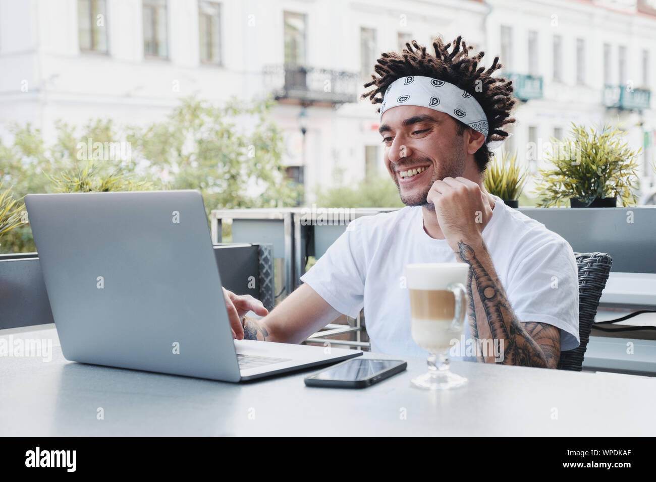 Aufgeregt hipster Kerl mit Dreadlocks Frisur freuen sich über den Gewinn eines Internet lotterie Wetten auf der Website auf dem Laptop. Gut aussehender bärtiger Mann feiern Stockfoto