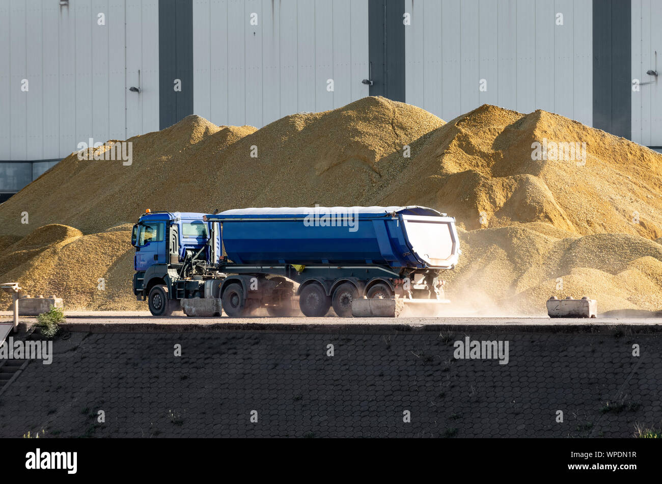 LKW fährt vor riesigen Sandpfählen auf einer Plattform. Stockfoto