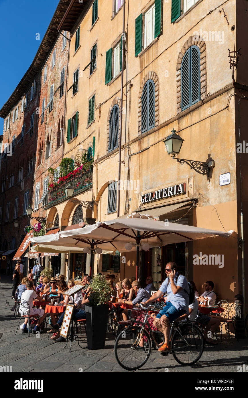 Ein beschäftigter Gelateria Café Bar in der Dämmerung in der Piazza San Michele, Lucca, Toskana, Italien. Stockfoto