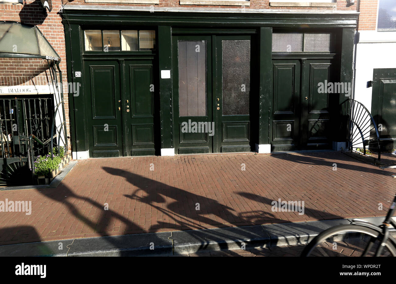 Einen langen Schatten eines Radfahrers, vorbei an den historischen Anne Frank Haus in der Prinsengracht 263, Amsterdam, Holland. Stockfoto