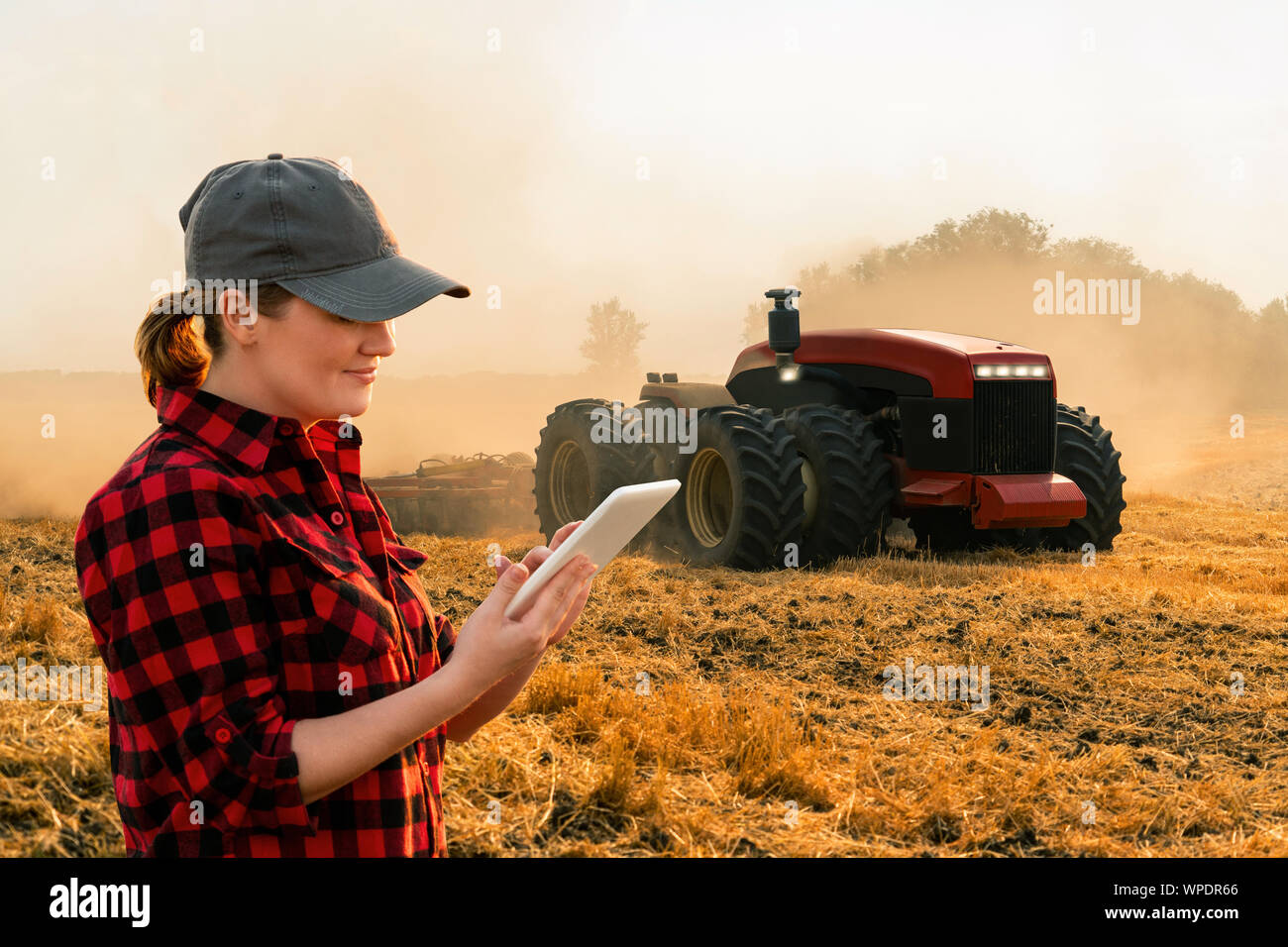 Eine Bäuerin mit digitalen Tablet steuert eine autonome Traktor auf einem smart Farm Stockfoto