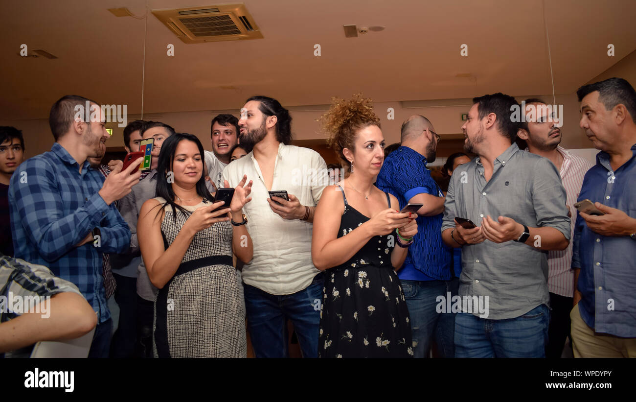 Kollegen versammelten sich auf einer Firmenfeier, benutzten Smartphones und pflegten bei einer zwanglosen Firmenveranstaltung in einem Innenbereich Kontakte. Stockfoto