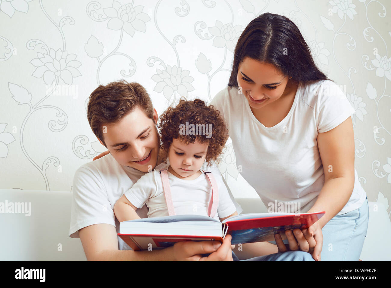 Mutter und Vater mit Kindern ein Buch zu lesen, während er auf dem Sofa Stockfoto