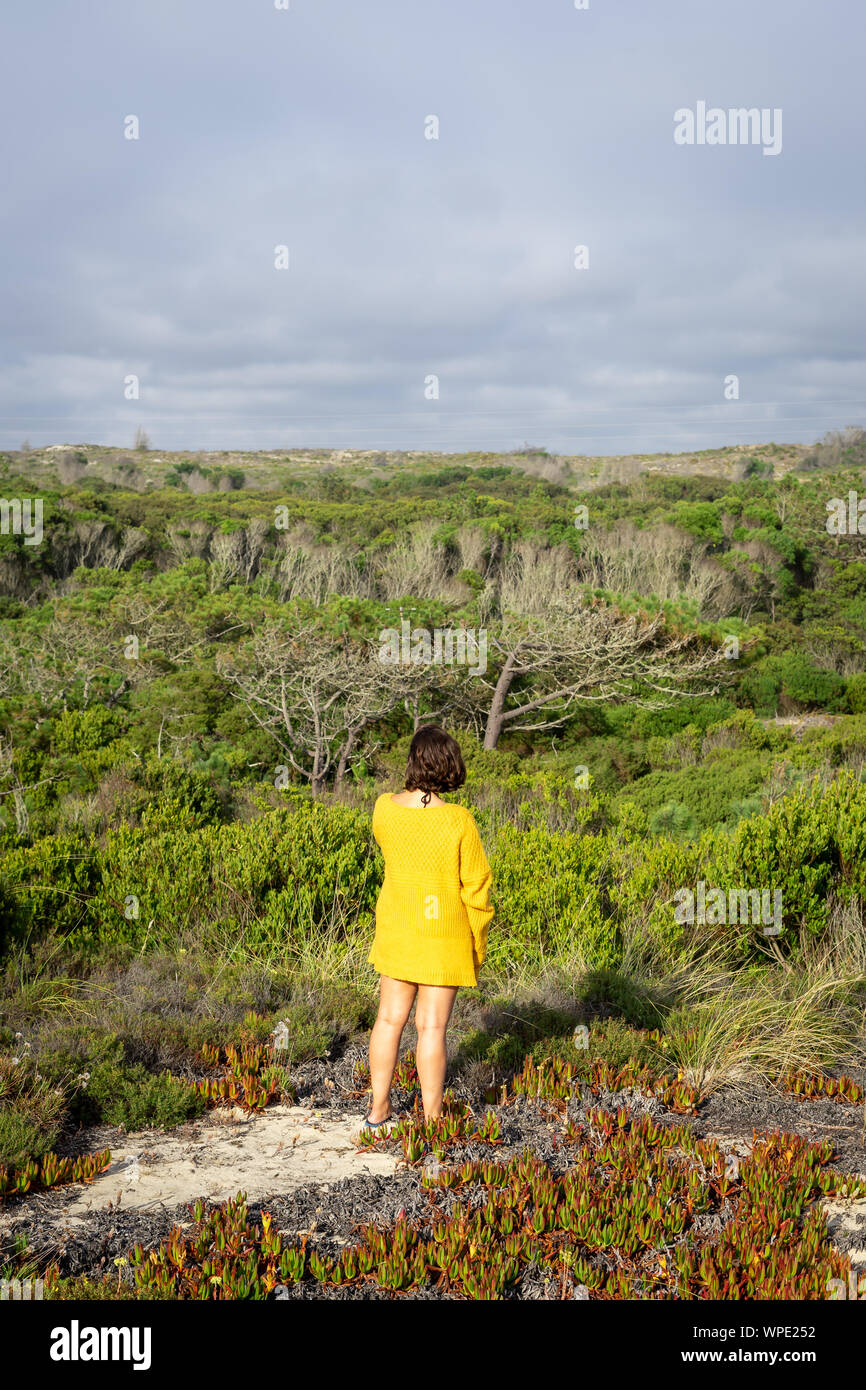 Mädchen, Ansicht von der Rückseite und an der Seite stand auf der Wiese mit Blick auf den Strand von der Spitze eines Berges. Stockfoto