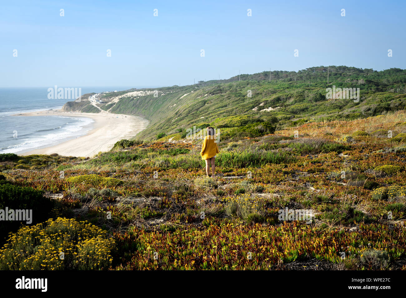 Mädchen, Ansicht von der Rückseite und an der Seite stand auf der Wiese mit Blick auf den Strand von der Spitze eines Berges. Stockfoto