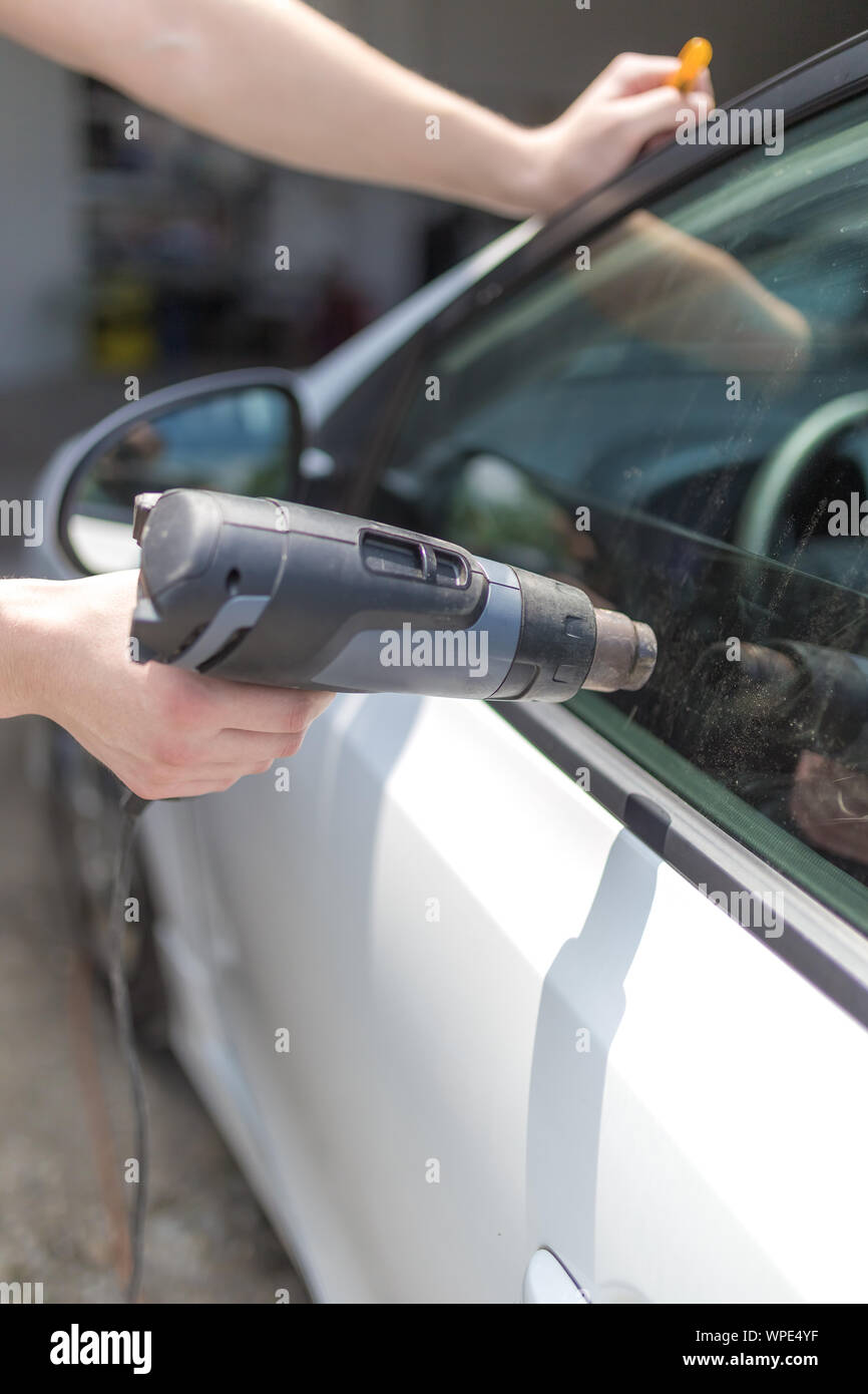 Mitarbeiter entfernen Auto Fensterfolie Folie mit Heißluftpistole