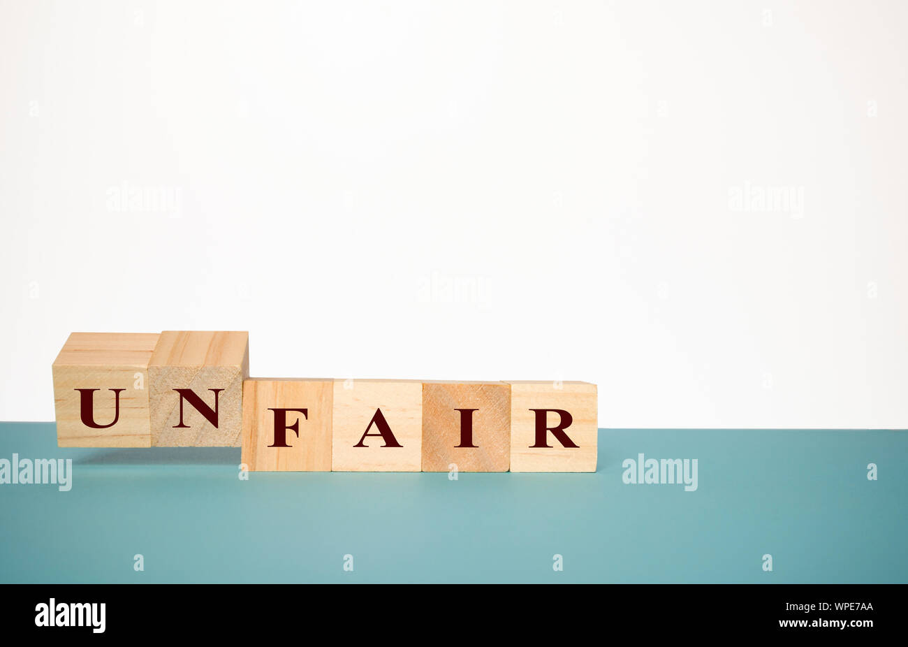 Schlagen Zwei hölzerne Würfel das Wort Unfair fair auf neutralem Hintergrund zu ändern Stockfoto