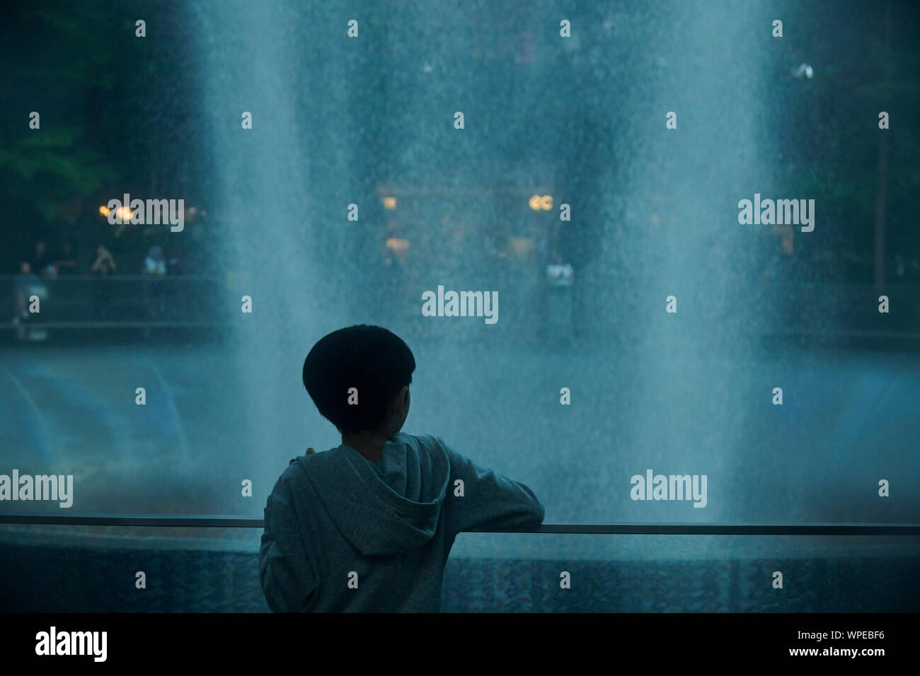 Nette junge asiatische junge Stehend vor dem Regen Vortex an Juwel in Changi Airport Stockfoto