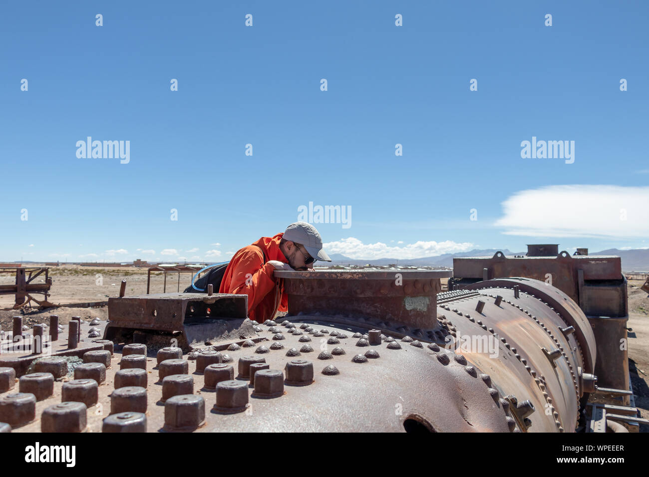 Junge kaukasier neugierig Mann an den verlassenen alten Dampflokomotive, Großer Zug Friedhof oder Dampflokomotiven Friedhof von Uyuni, Bolivien Stockfoto