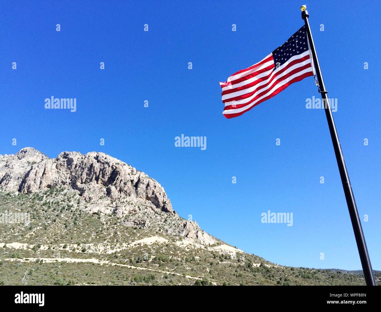 Low Angle View der amerikanischen Flagge am Frühling in den Bergen gegen den klaren blauen Himmel Stockfoto