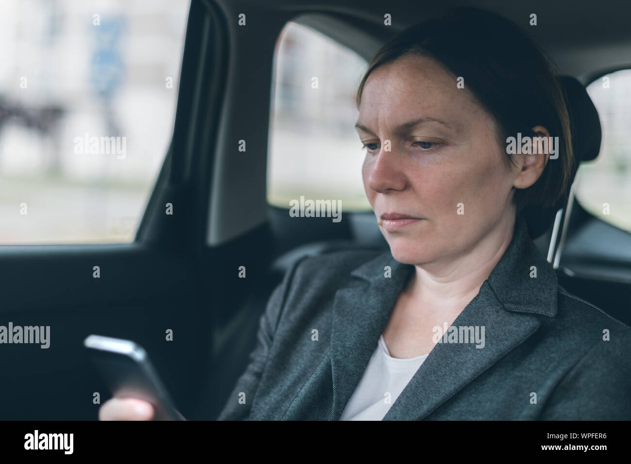 Geschäftsfrau SMS auf Handy im Auto sitzend auf dem Rücksitz, selektiver Fokus Stockfoto