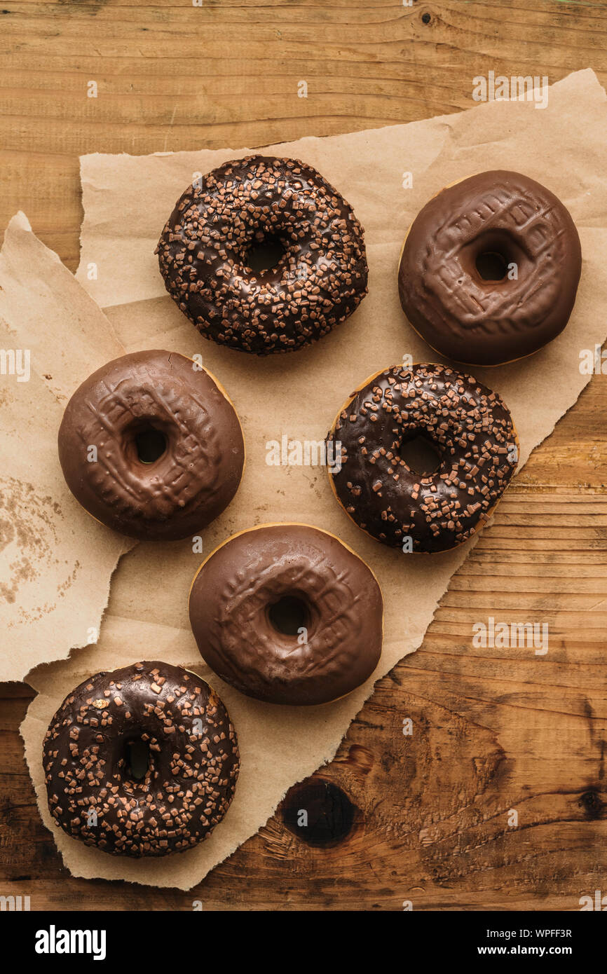 Leckere Schokolade Donuts mit Sahne und Krümel auf rustikalen Holztisch direkt von oben gesehen Stockfoto