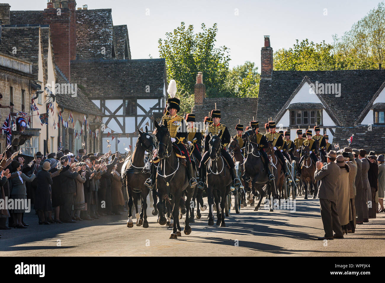 Die Könige Troop Royal Horse artillery während der Dreharbeiten zu einem Film Version von Smash TV-hit Downton Abbey für das Kino. Die Szene wurde erschossen in der Hohen St der National Trust Dorf Lacock in Wiltshire mit 80 Pferden und Gewehren und über 250 Extras zujubeln und wehenden Fahnen wie die Parade vorbei. Stockfoto