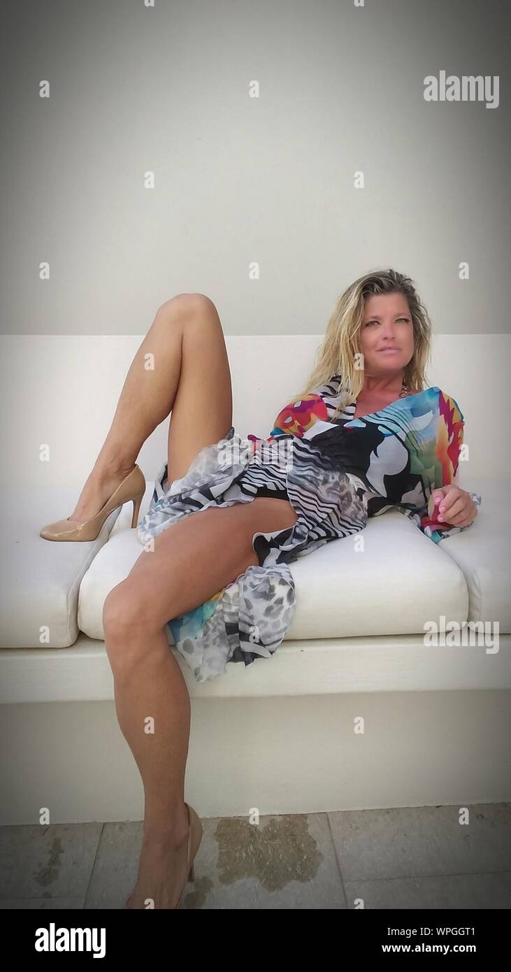 Porträt der Frau in Bikini Abdeckung nach oben, während er auf einem Sofa gegen die Wand Stockfoto