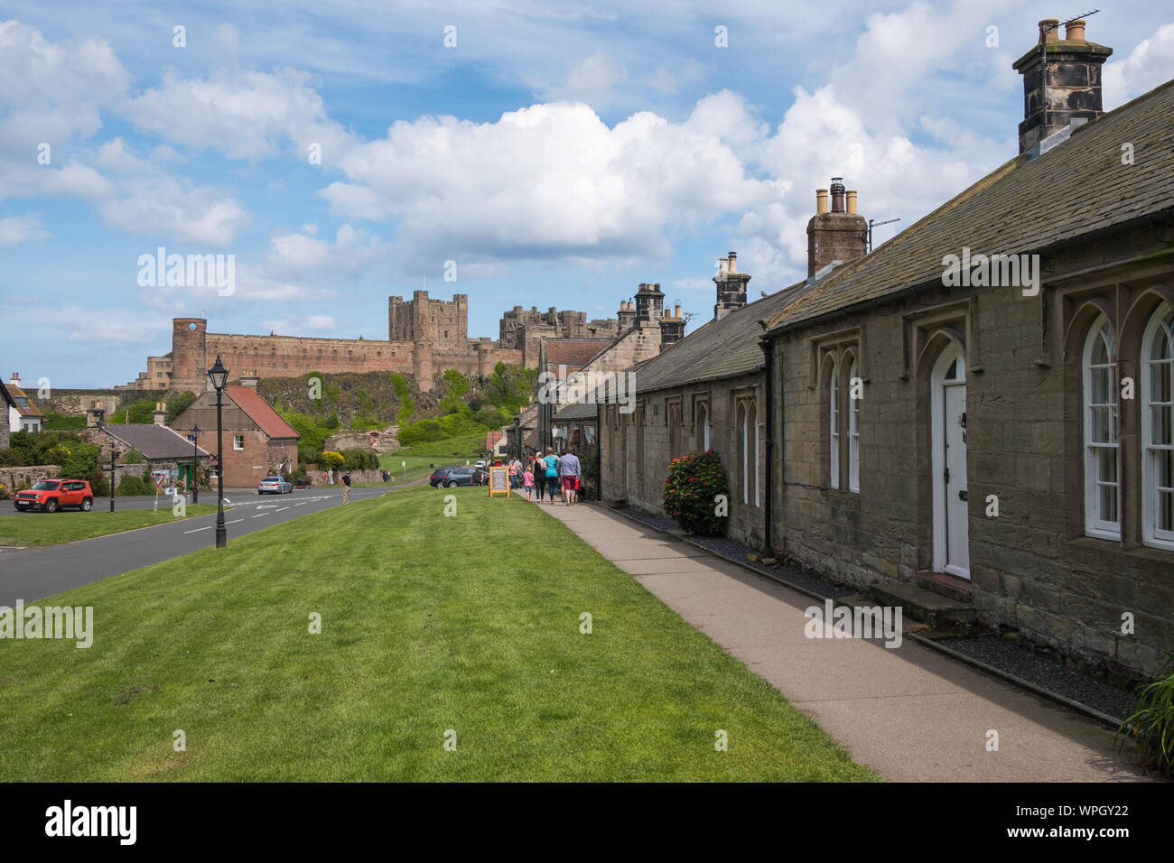 Auf der Suche Front Street in der Ortschaft Bamburgh an der Küste von Northumberland, Großbritannien mit Bamburgh Castle im Hintergrund Stockfoto