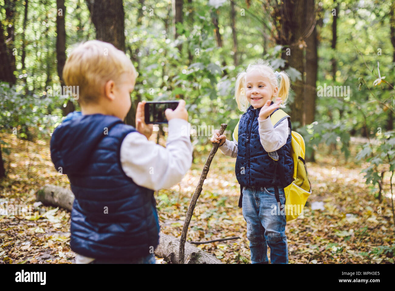 Kinder im Vorschulalter kaukasischen Bruder und Schwester Bilder von einander auf Handy Kamera in Forest Park Herbst. Thema der Hobby- und Aktiv Stockfoto