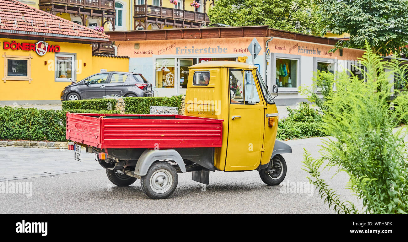 Garmisch-Partenkirchen, Deutschland, 10. August, 2019: Drei Rad italienische Pickup Truck mit gelben und roten Ladefläche Reisen durch eine deutsche Stadt Stockfoto