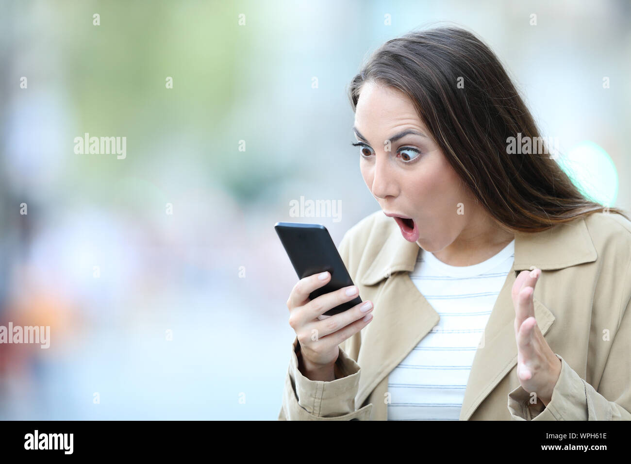 Schockiert Frau finden überraschende Nachrichten auf Smart Phone auf der Straße Stockfoto