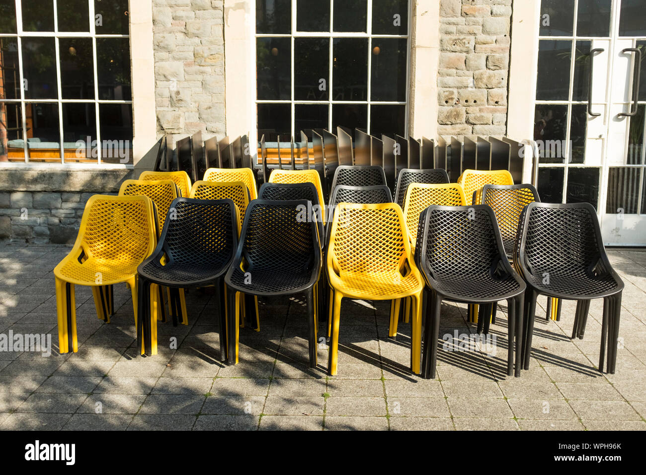Schwarz und Gelb Kunststoff Stühle links außerhalb des Restaurant Cafe, Bristol, Großbritannien Stockfoto