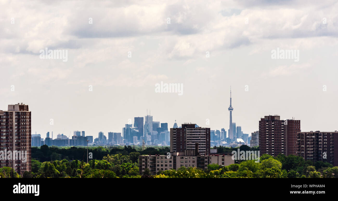 TORONTO, ONTARIO, Kanada - 10. JULI 2016: Altbauwohnungen stehen unter Bäumen in einem Vorort von Etobicoke, mit der dichten Downtown in der Ferne. Stockfoto