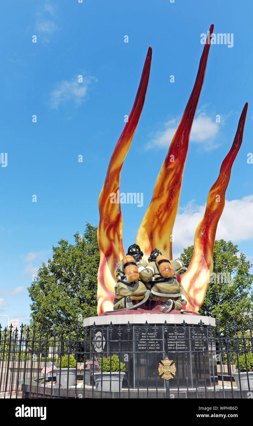 Zwei Feuerwehrleute bekämpfen eine Flamme im Cleveland Firefighters Memorial, eine Fiberglas-Skulptur, die die in der Dienstlinie in Cleveland Getöteten ehrt. Stockfoto