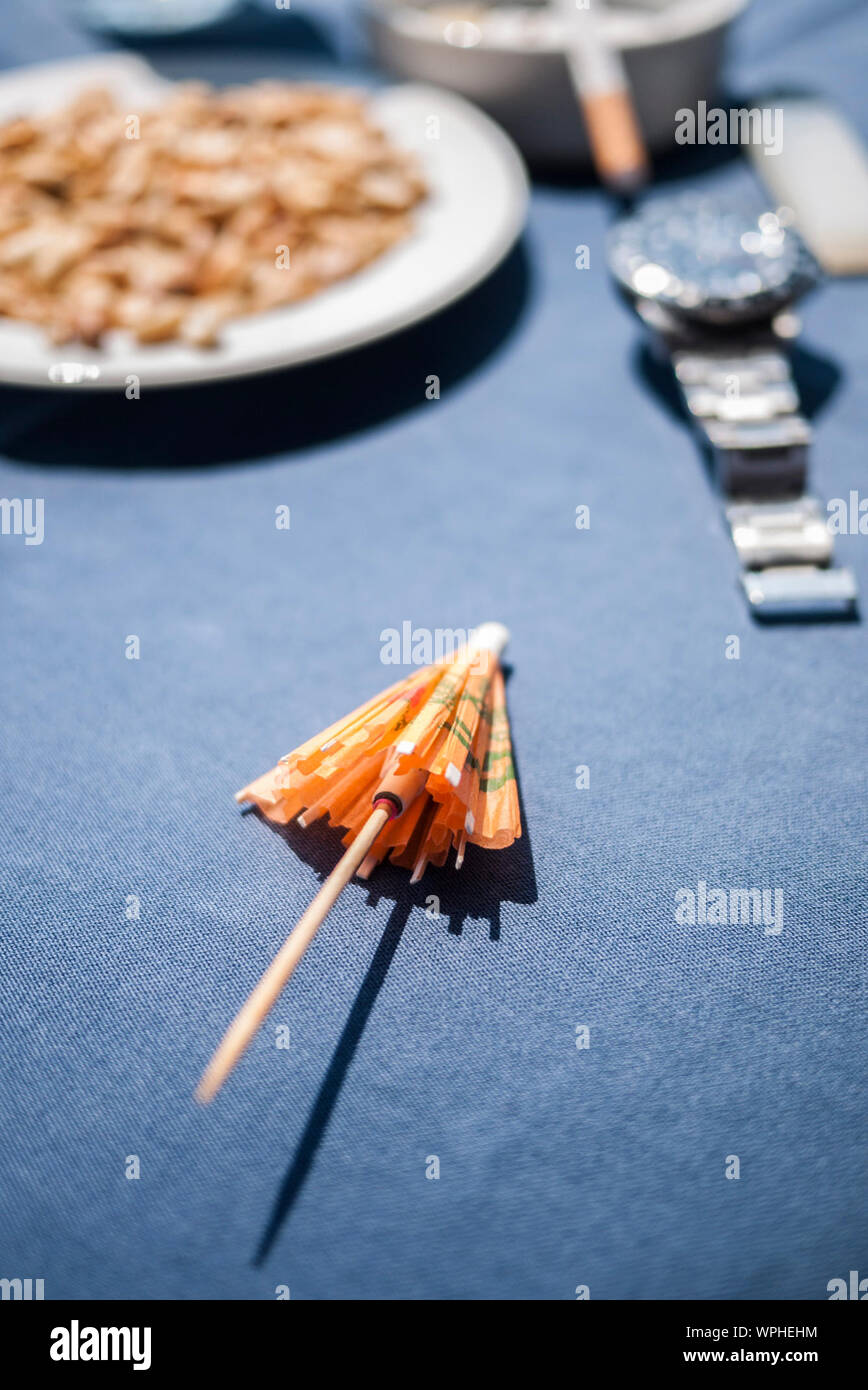 Cocktail Regenschirm auf einem Tisch mit Teller im Hintergrund Stockfoto