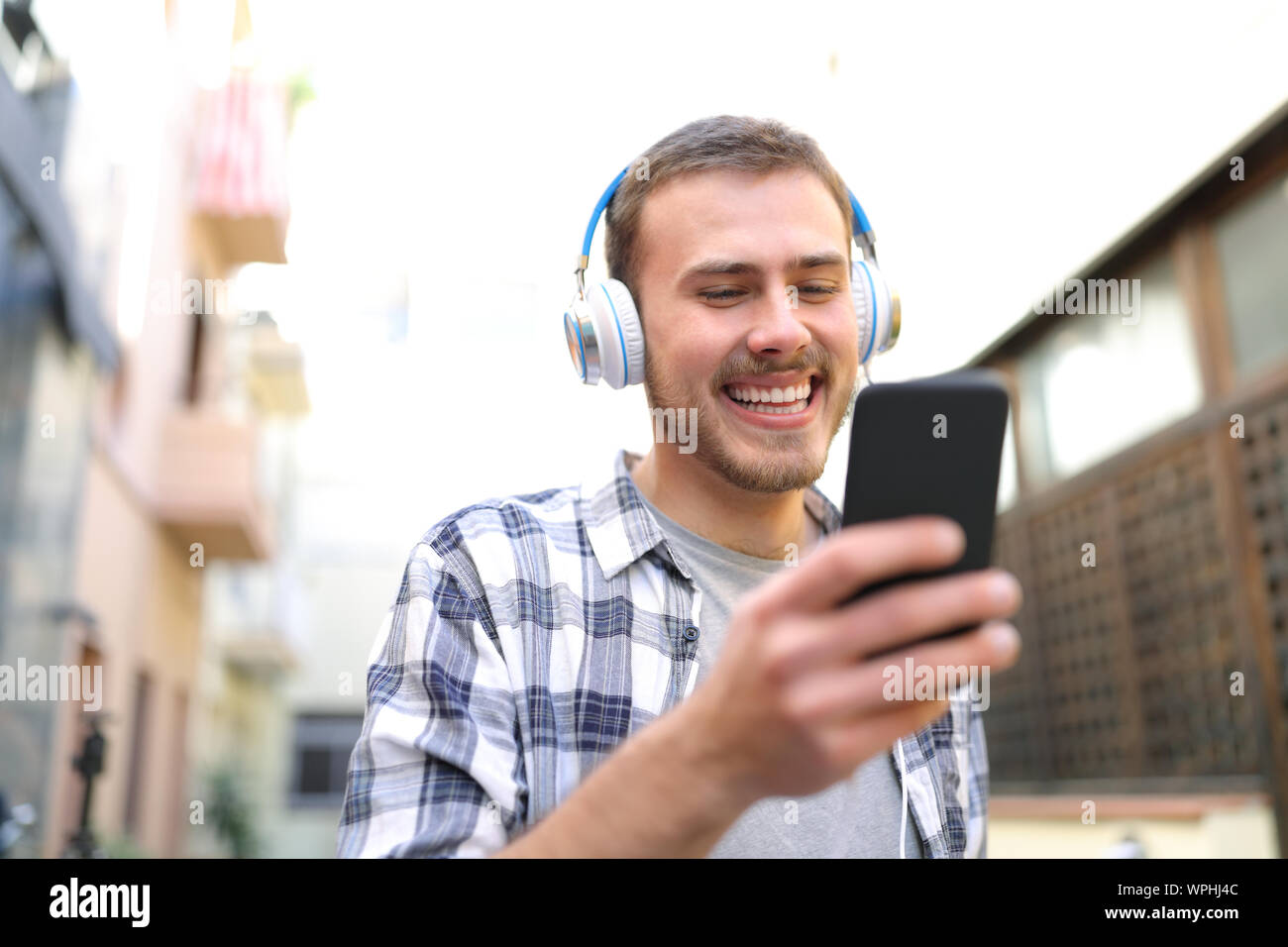 Glückliche Menschen Ansehen und Anhören von musinc von Smart Phone zu Fuß auf der Straße Stockfoto