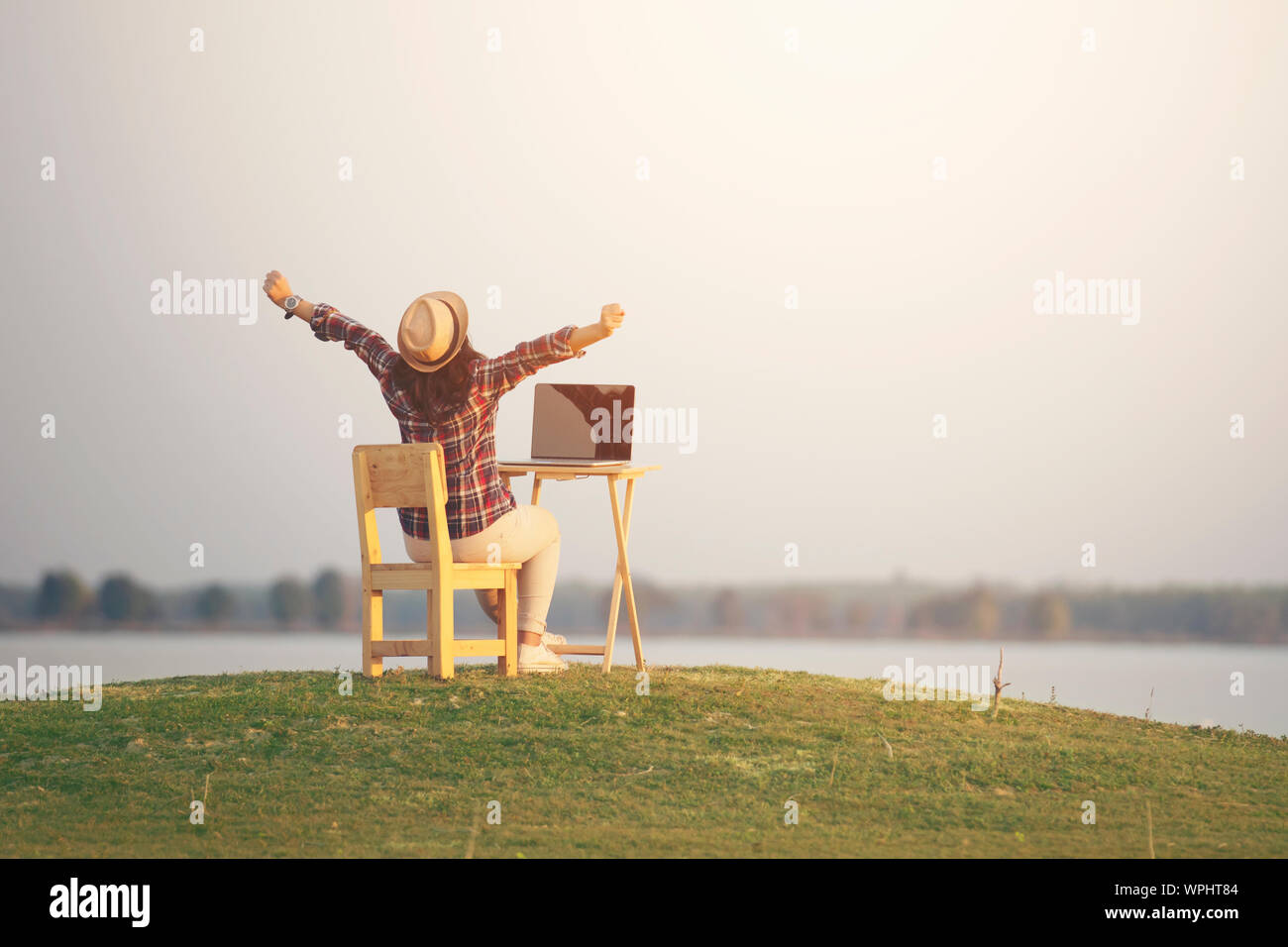 Frau mit Laptop mit offenem Arm in Natur Hintergrund Stockfoto