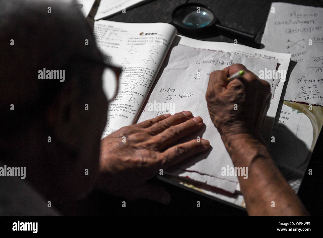 (190909) - CHANGSHA, Sept. 9, 2019 (Xinhua) - Tang Shangjun decodiert eine mathematische Frage zu Hause in Wuhan Dorf Anhua County in Yiyang City, Central China Provinz Hunan, Sept. 7, 2019. Ein Holzhaus steht allein in den tiefen Bergen durch einen lebhaften grünen Decke von Bäumen bedeckt, nicht nur als Wohnung, sondern auch als ein Klassenzimmer, wo Tang Shangjun Nachhilfe Studenten Seit mehr als 20 Jahren. Tang, einem 92-jährigen ländlichen Lehrer, nachhilfe begonnen, die Kinder durch ihre Eltern mit Migrationshintergrund kostenlos Links in Wuhan Dorf im Jahre 1997, 10 Jahre nachdem er zog sich von der Lehre in Anhua Coun Stockfoto