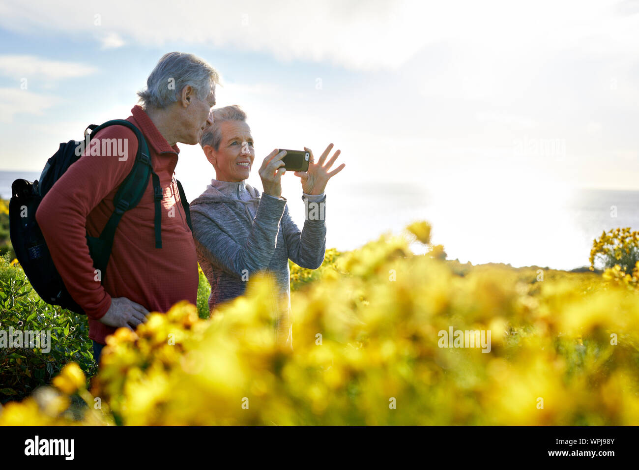 Älterer Mann an Frau Fotografieren durch Smart Phone, während gegen Sky standing Stockfoto