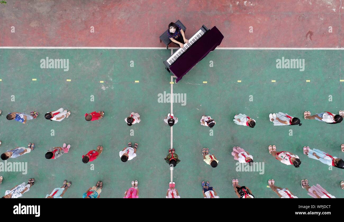 (190909) - NANCHANG, Sept. 9, 2019 (Xinhua) - Luftaufnahme auf Sept. 1, 2019 zeigt Tu Youyou das Klavier spielen zu begrüßen Studenten während der Eröffnung des neuen Semester an Shangban Grundschule in Luoting Township, Wanli Bezirk von Nanchang Stadt, im Osten der chinesischen Provinz Jiangxi. Nach dem Abitur in 2013 von der normalen Ausbildung, Tu arbeitete als Assistent in einer Ausbildungseinrichtung und Gemeinschaft funktionieren, aber Sie hat immer davon geträumt, ein Lehrer. Im Jahr 2016 legte sie der Lehrer Einstellung Prüfung der Provinz Jiangxi und wurde zu einem ländlichen Lehrer. In den letzten drei Jahren, Tu Stockfoto
