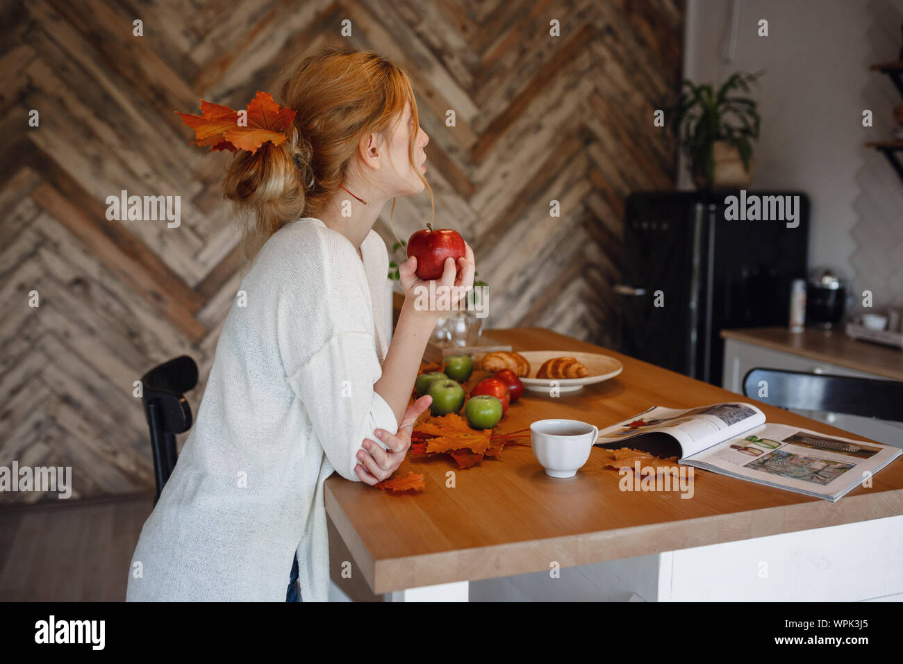 Sseries Herbst in der Küche, Melancholie und warm.. Entspannen in kaltem Wetter. rothaarige Mädchen genießen Äpfel in der Küche Stockfoto