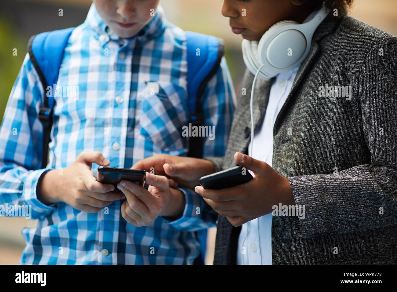 Close-up von zwei Freunden in Freizeitkleidung holding Handys zeigen Sie an und diskutieren online Spiele im Freien Stockfoto