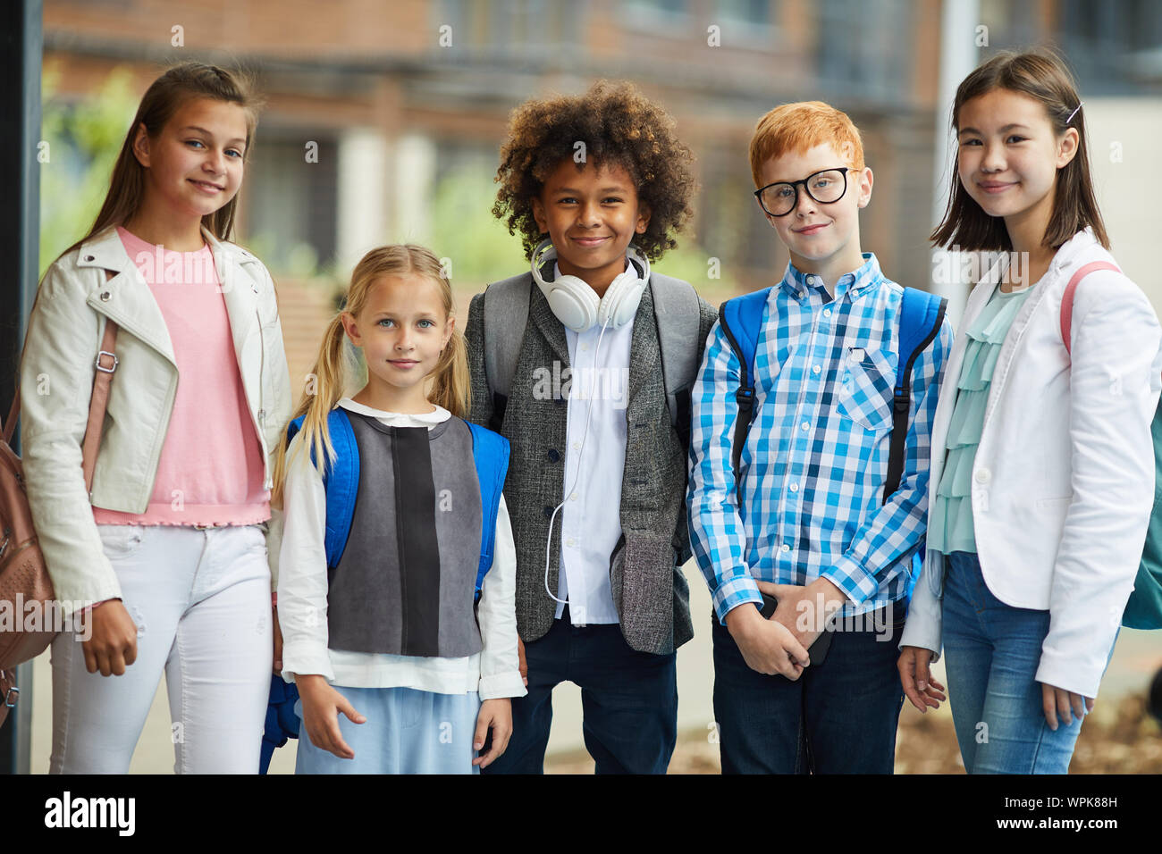 Gruppe von Multiethnischen elementare Studenten in Freizeitkleidung zusammen stehen und Lächeln auf die Kamera im Freien Stockfoto