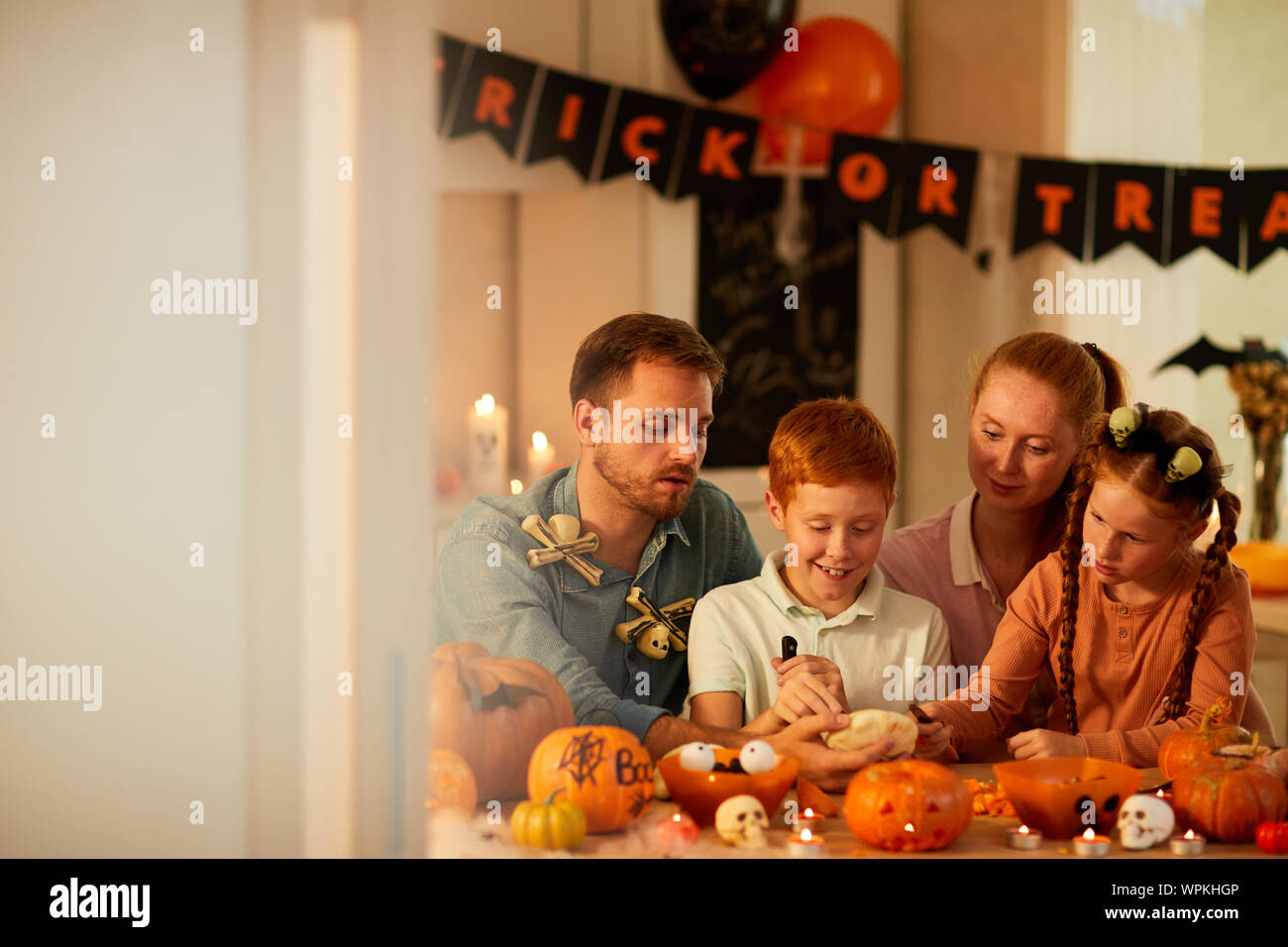 Glückliche Familie von vier Sitzen am Tisch Dekoration Kürbisse und Vorbereitung für die Halloween Urlaub Stockfoto