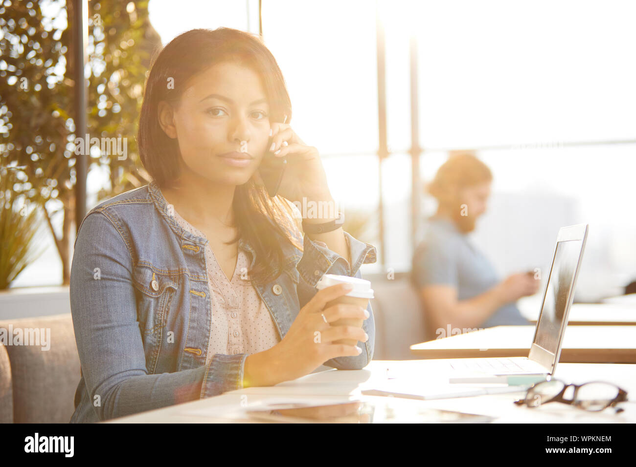 Porträt der jungen Geschäftsfrau in Freizeitkleidung Gespräch am Handy und Kamera beim Kaffeetrinken im Cafe Stockfoto