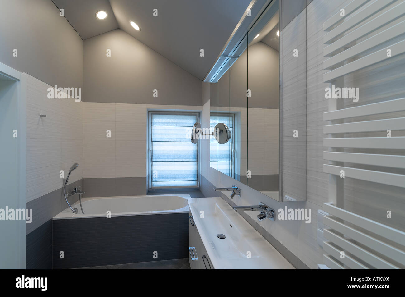 Das Innere eines modernen Bad mit Fenster in ein eigenes Haus. Badewanne, Schränke mit Spiegel und Waschbecken mit zwei Hähne Stockfoto