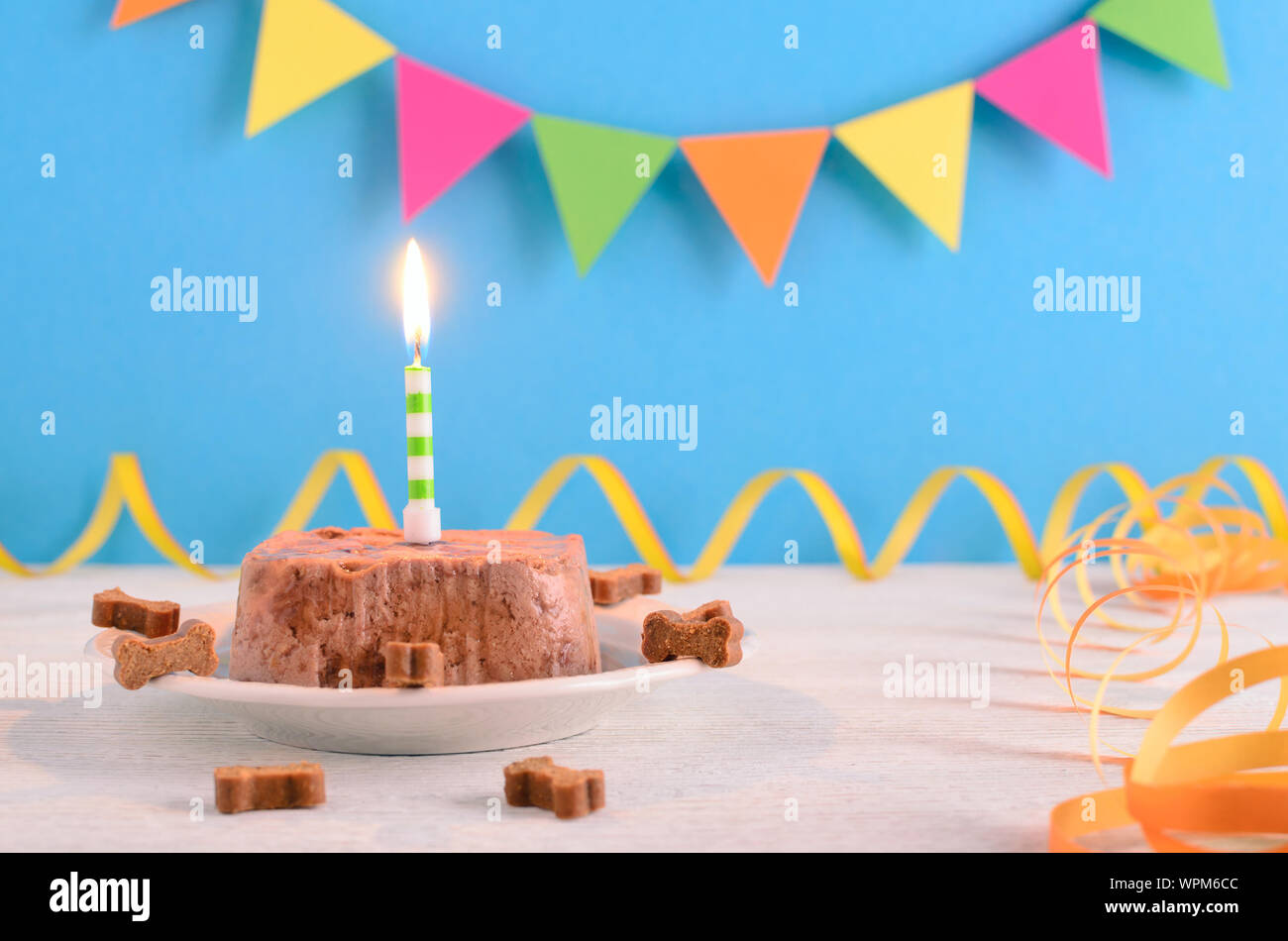 Happy Birthday Kuchen für Hund von Nassfutter und behandelt mit Kerze für Blue party Hintergrund Stockfoto
