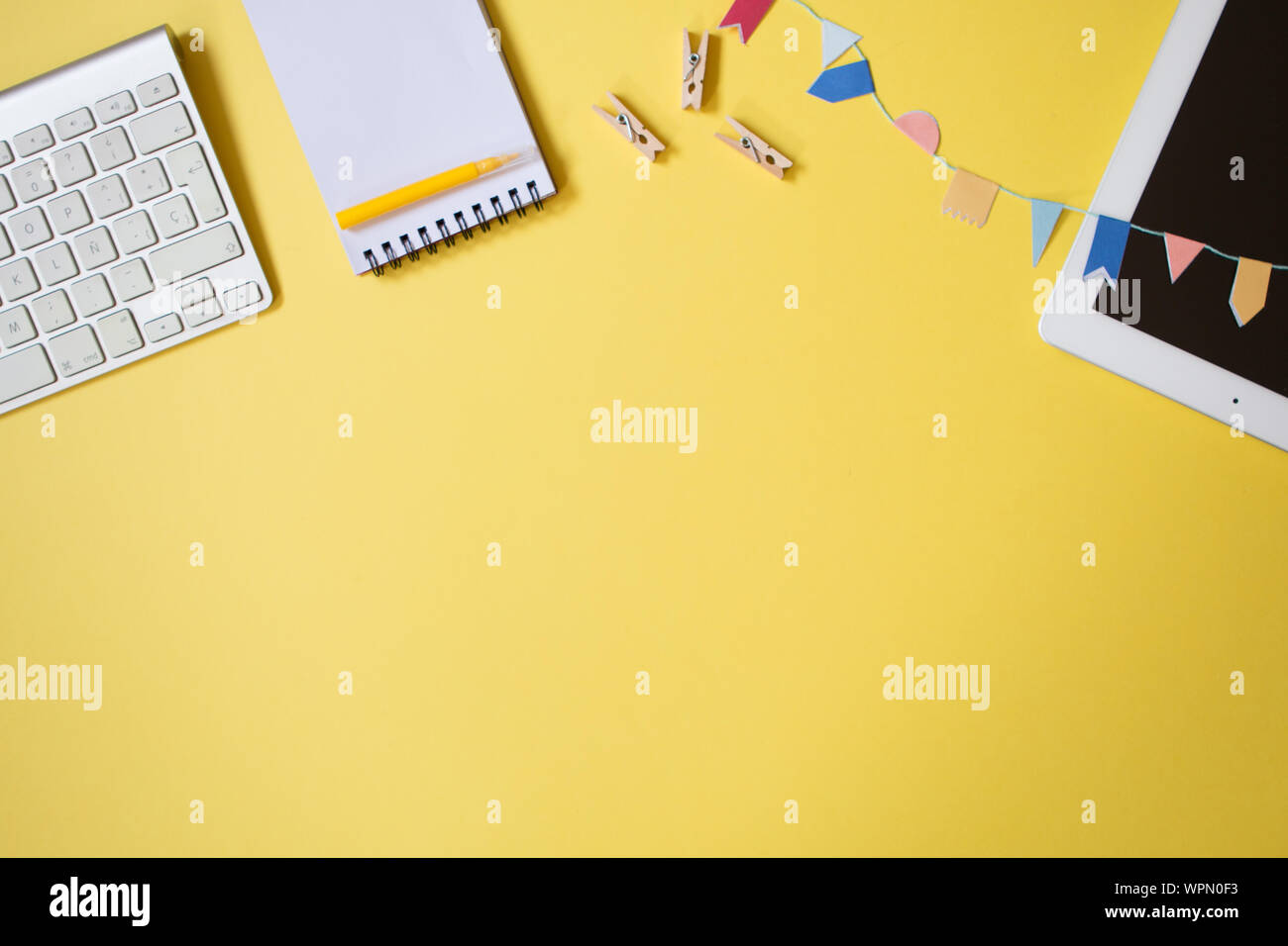 Minimale Blick von oben auf eine Jugend Tabelle Schreibtisch mit Laptop, Tastatur, Notebook, Pen und einige kleine Wäscheklammern. Freelancer Workplace Konzept auf Pastell Farbe Stockfoto