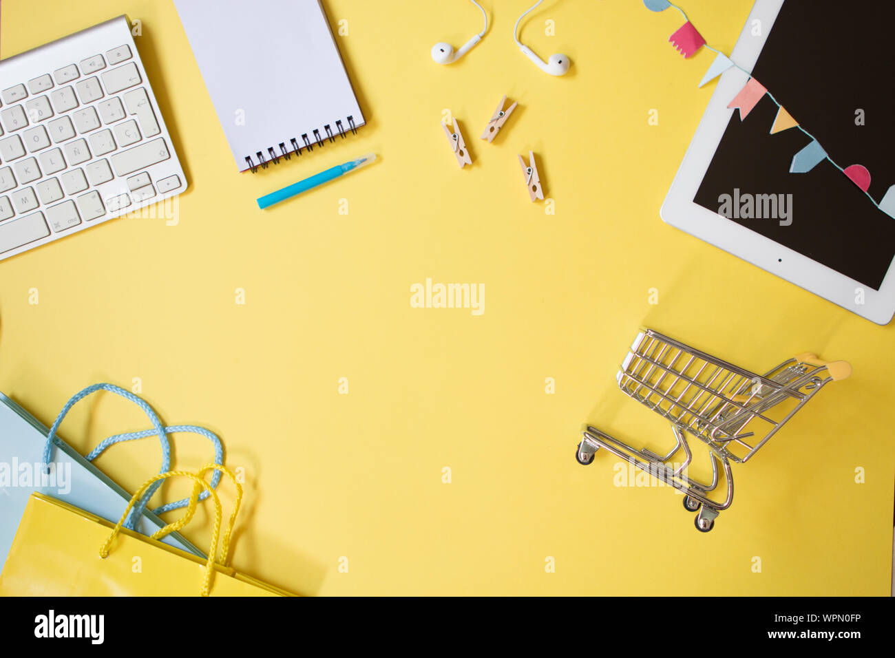 Blick von oben auf die minimale feminine Bürotisch Schreibtisch auf pastellfarbenen Hintergrund mit einer Tablette, kleine Katze, Notebook, Tastatur und einige Einkaufstaschen. Stockfoto