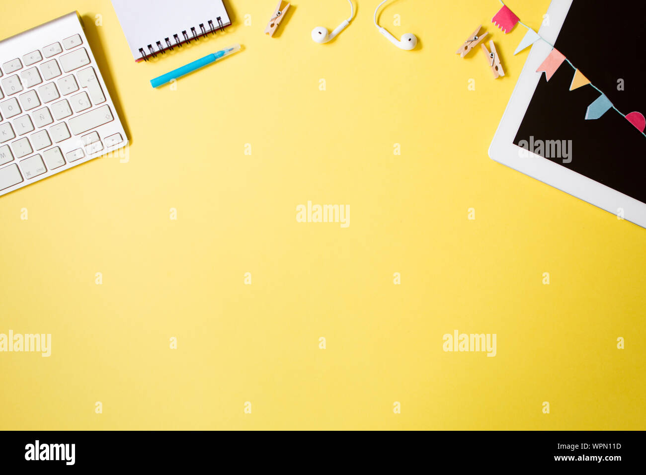 Flach top Blick auf Jugendliche Arbeitsbereich mit Tablet-PCS, Notebook, Marker, Wäscheklammern und Tastatur auf Gelb pastell Hintergrund. Platz für Text Stockfoto