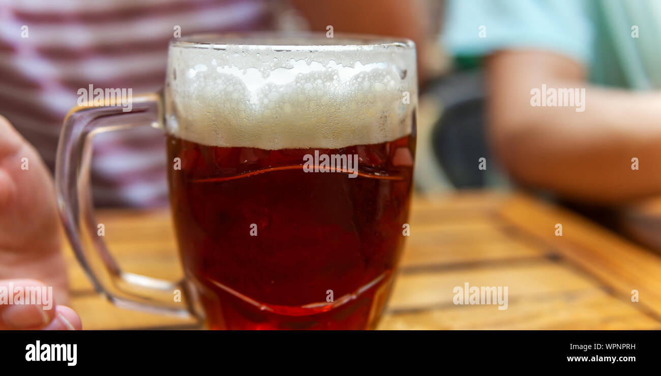 Der Mensch ist ein frisch gezapftes Glas Bier in der Hand Stockfoto