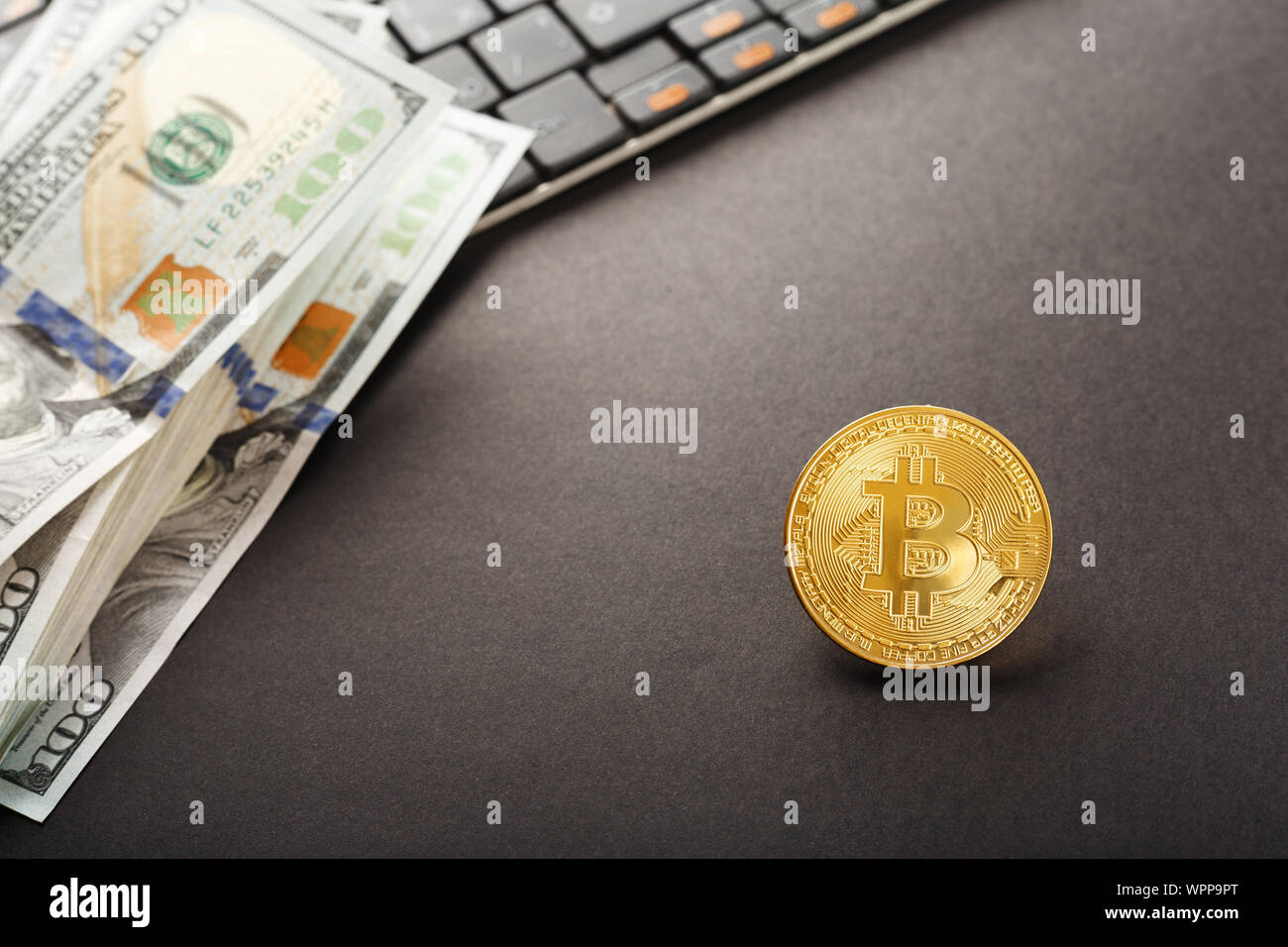 Nahaufnahme gold Bitcoin auf Dollar Banknote über Computer auf schwarzem Hintergrund. Stockfoto