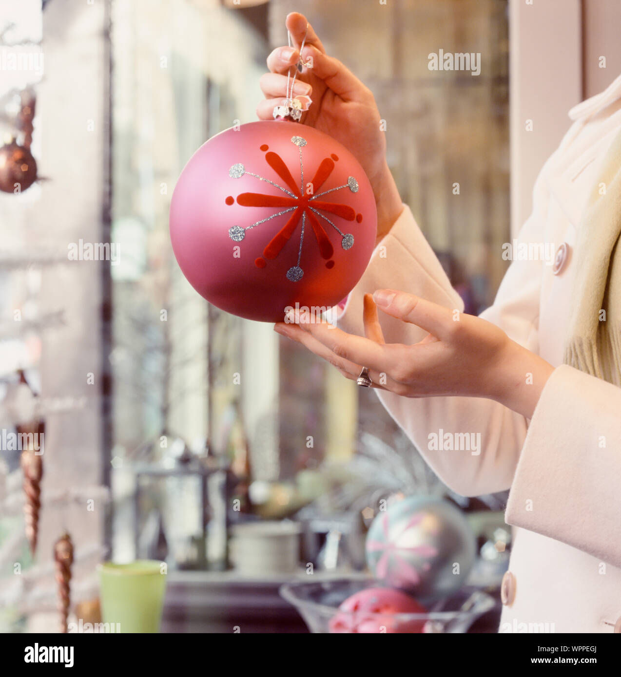 Woman's Hände, die Lust auf Weihnachten schmuck Christbaumkugel in Shop Shop. Einkaufsmöglichkeiten für Geschenke Dekorationen. Stockfoto